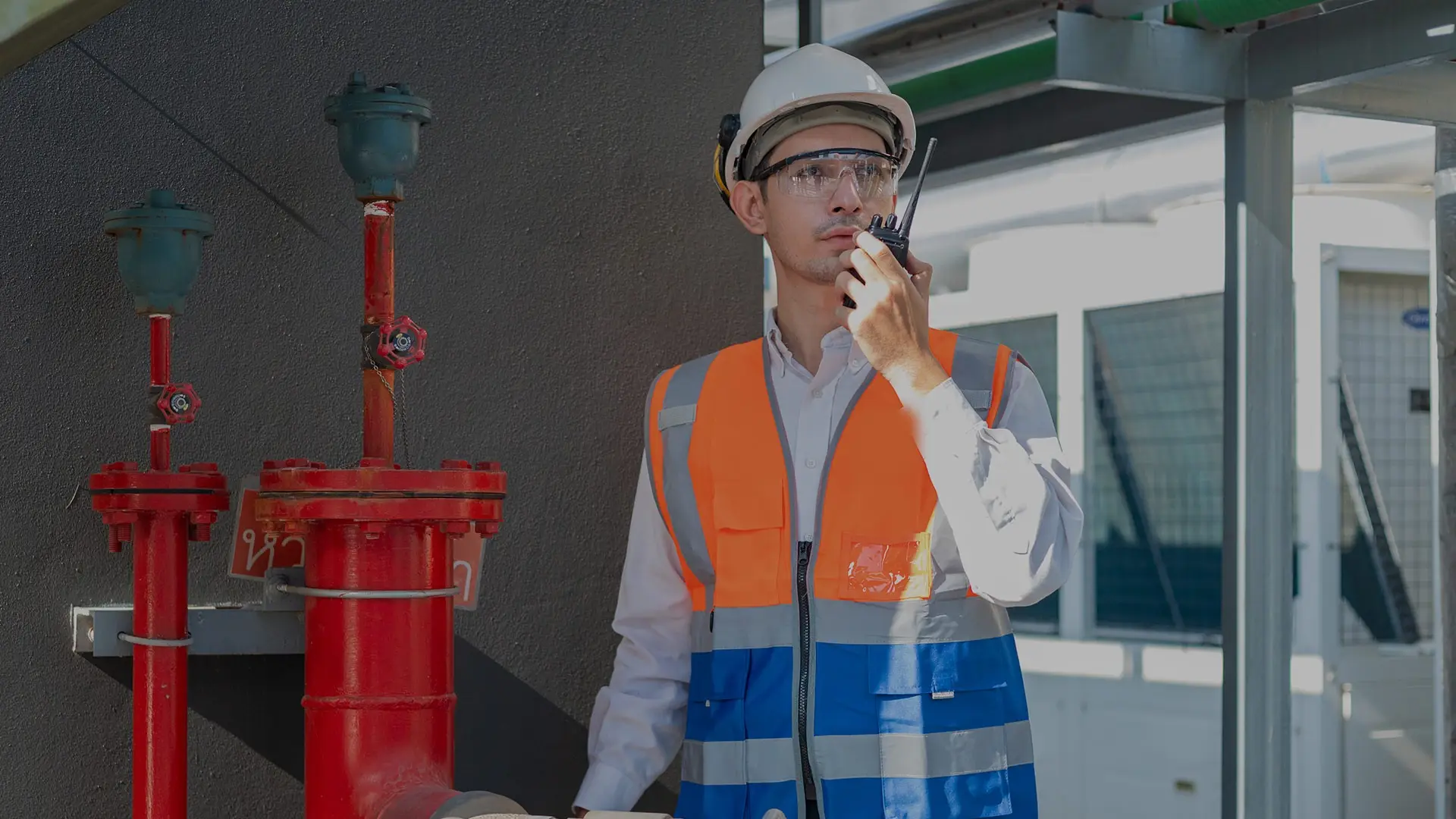 Brandwache mit Helm und Funkgerät an roten Löschwasserleitungen
