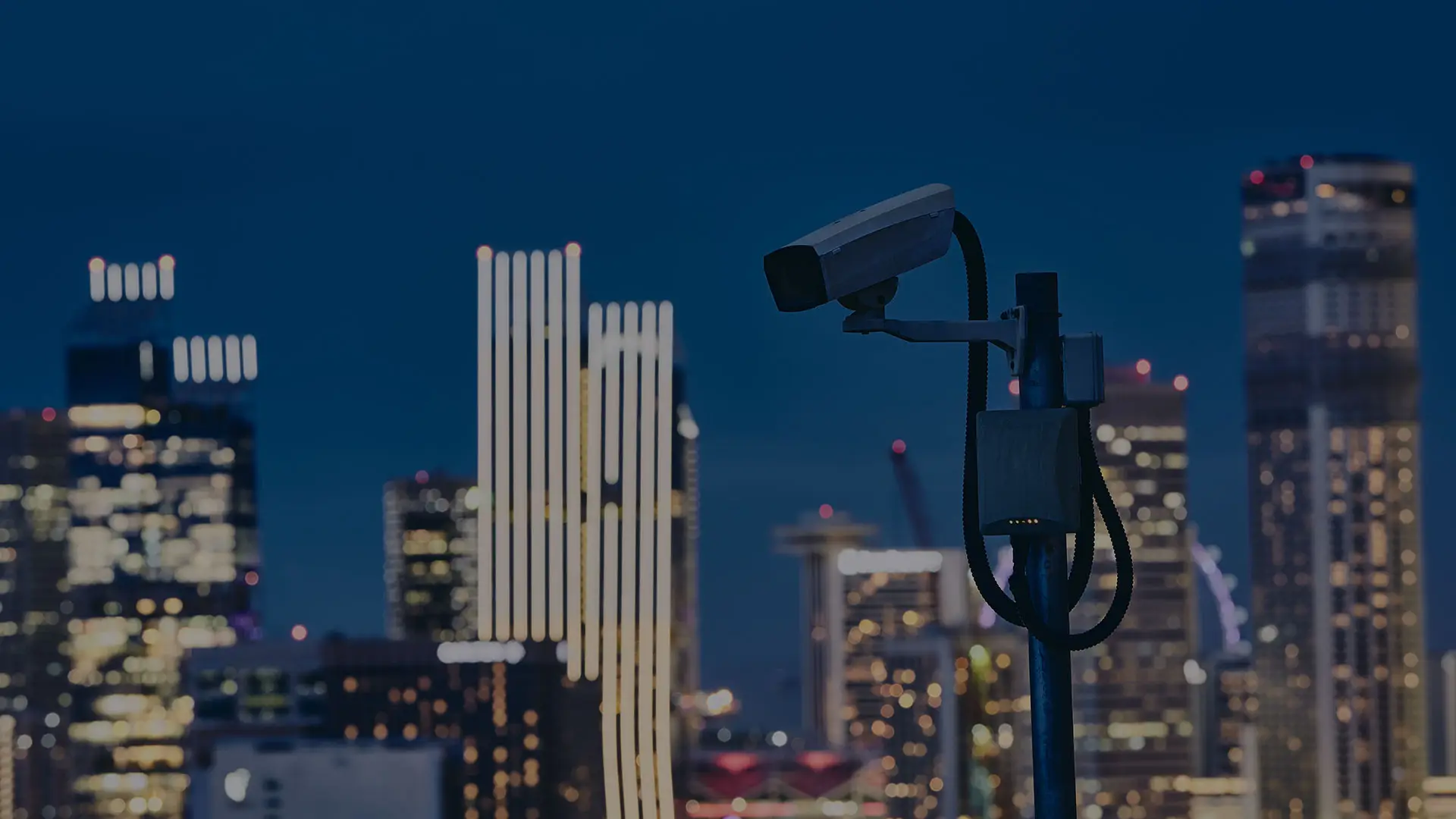 Überwachungskamera vor beleuchteter Stadtsilhouette bei Nacht