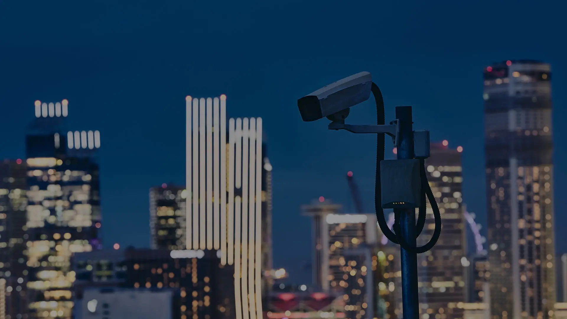Überwachungskamera vor beleuchteter Stadtsilhouette bei Nacht