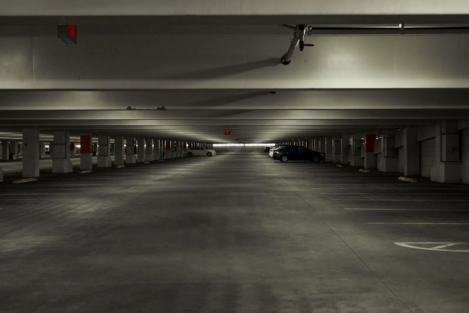 Parkhausebene mit Betonpfeilern und wenigen parkenden Autos in gedämpftem Licht