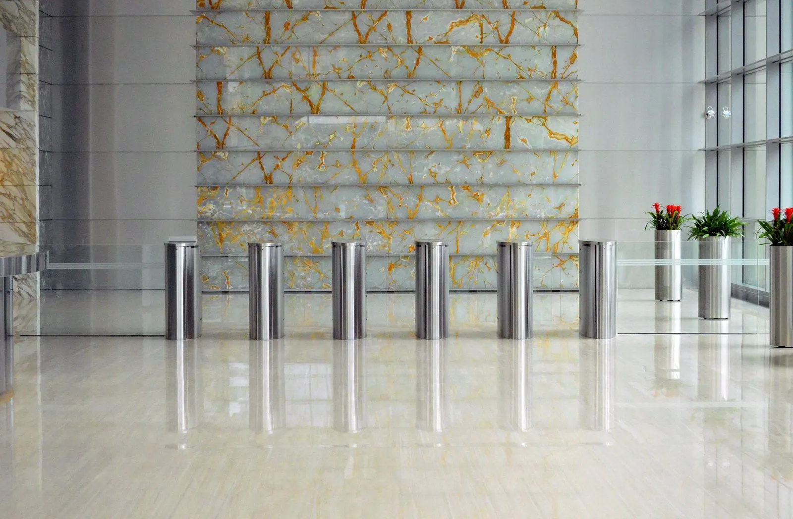 Moderne Bürolobby mit Edelstahl-Zutrittsschleusen vor einer hellen Marmorwand