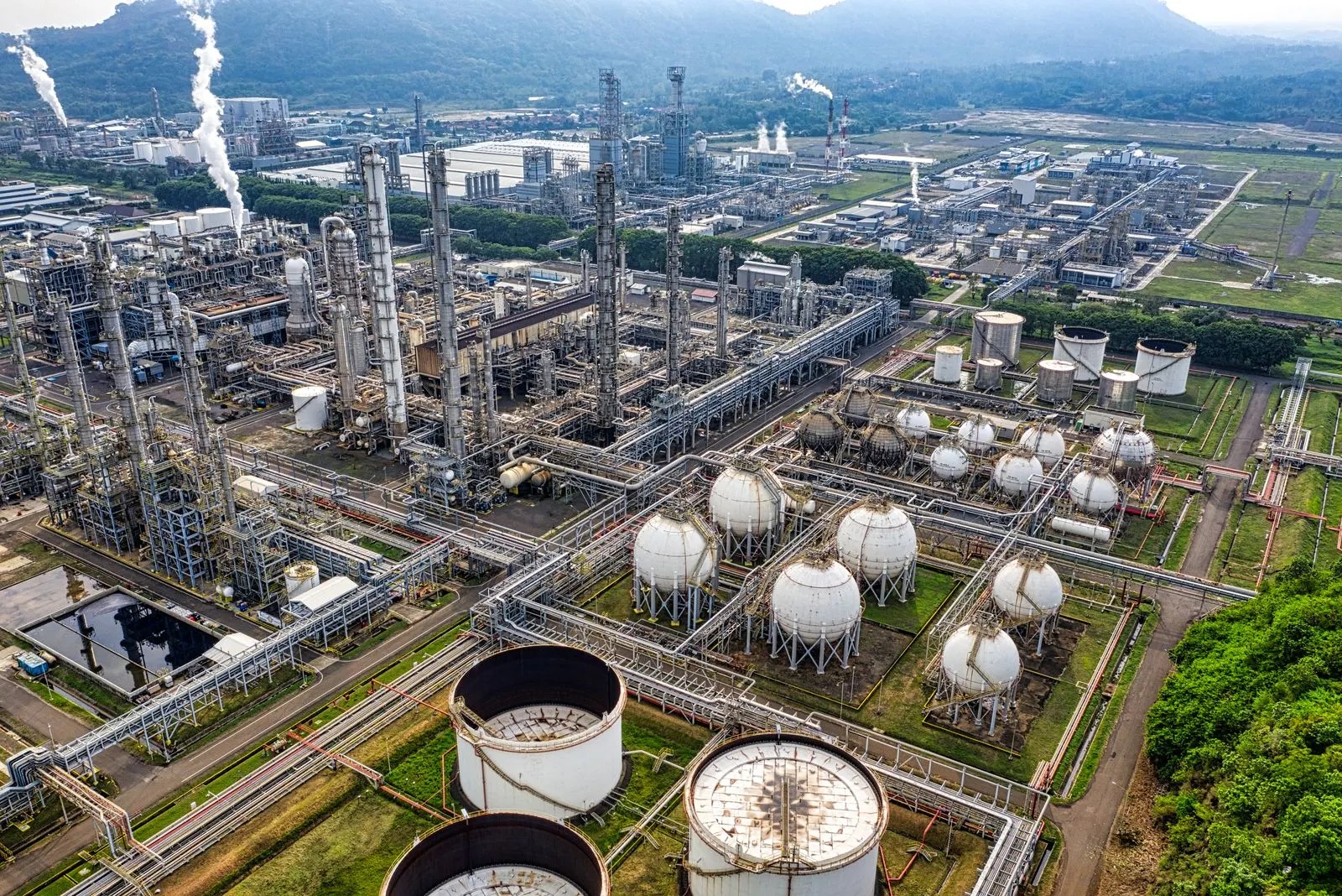 Luftaufnahme eines weitläufigen Industrieparks mit Prozessanlagen, Rohrbrücken und Tanklagern